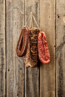 Assortment of dried meat and sausages hanging on a barn wall