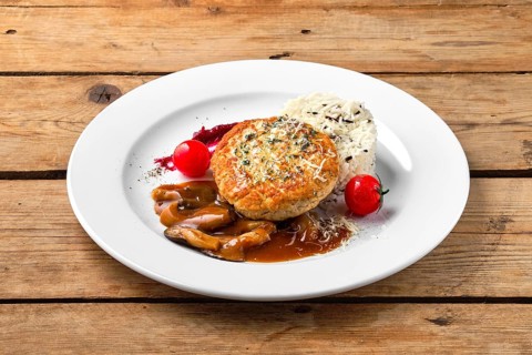 Beef cutlet with rice and mushroom sauce on rustic table