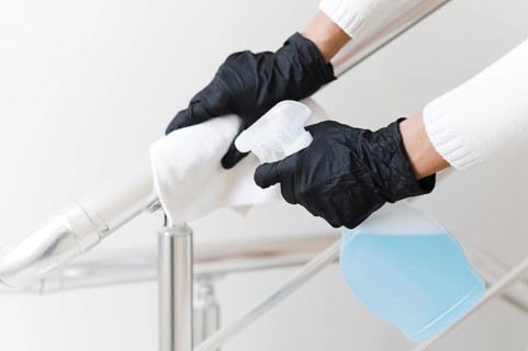 Hands with gloves disinfecting hand rail