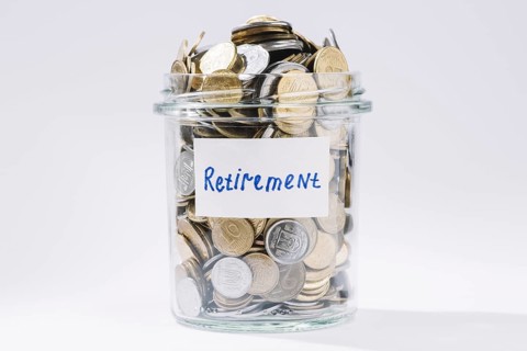 Retirement glass container full coins white backdrop