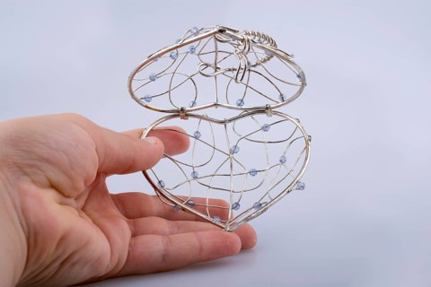 Heart shaped silver color metal wire cage in hand