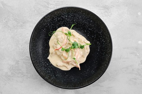 Pieces of chicken meat with bell pepper and creamy white sauce on a plate