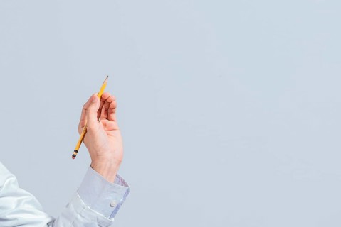 Hand with a pencil pointing at a blank space. Male hand holding a pencil on a blank. Man fingers holding a pencil with blank space. Person's hands holding a pencil on a space for text