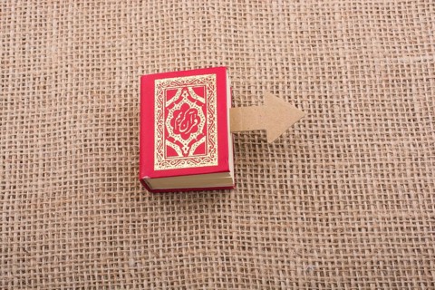Paper arrow and Islamic Holy Book Quran in mini size