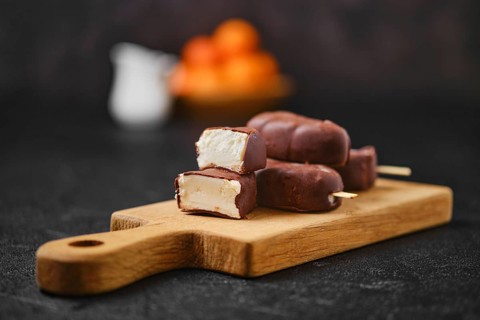 Homemade curd bars in chocolate on wooden board