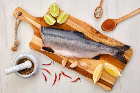 Top view of raw fresh headless pink salmon on wooden cutting board
