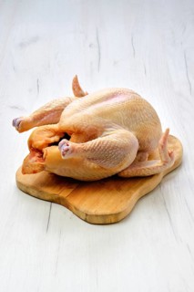 Fresh raw whole farm chicken on wooden cutting board