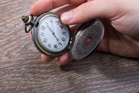 Retro style pocket watch in hand on black background