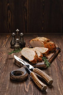 Pork strip loin baked in oven on wooden cutting board