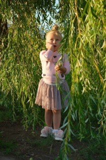 Cute little child under willow tree in park