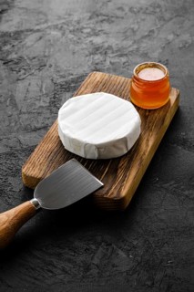 Piece of soft brie or camembert cheese on cutting board