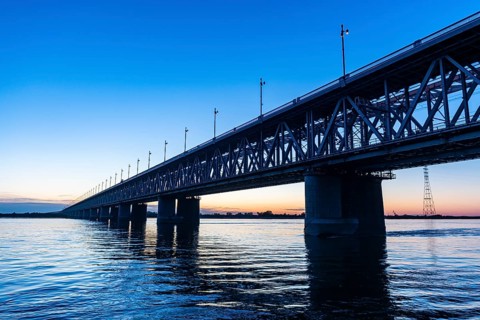 Giant bridge spanning over the Amur river at sunset