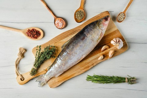 Overhead view of raw frozen unpeeled omul on wooden cutting board