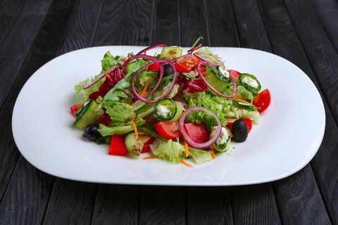 Salad with feta cheese rolled in cucumber slices with tomato and red onion