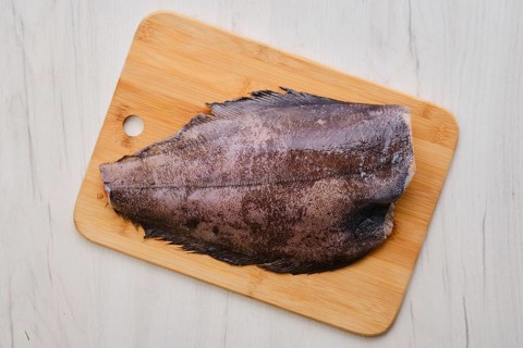 Top view of raw fresh halibut without head on wooden cutting board