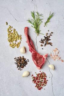 Composition with raw doe ribs with spice and herb over concrete background