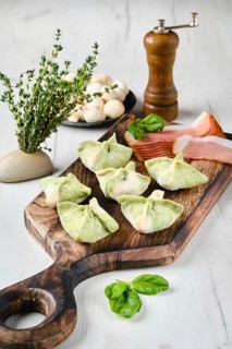 Dumplings stuffed with smoked ham and mushrooms on wooden serving board