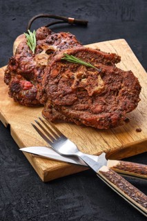 Grilled lamb neck on wooden cutting board