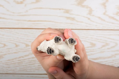 Hand holding a Polar bear model on a wooden background