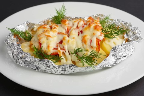 Closeup view of fried in foil sea fish and potato with paprika and cheese