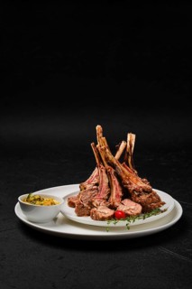 Grilled rack of lamb on a plate with spicy sauce
