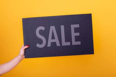 Female hand holding a Sale poster. Studio shot