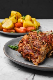 Closeup view of pulled lamb shoulder meat baked in oven with potato and carrot on marble table