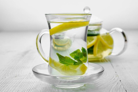 Antioxidant hot drink with lemon and mint in transparent tea pot and glass