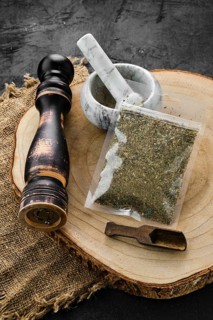 Wooden cross section with Provencal herbs in plastic package and stone mortar and mill