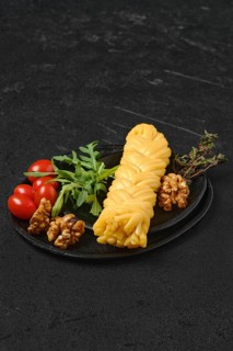 Smoked braided cheese with walnuts and tomatoes on a plate