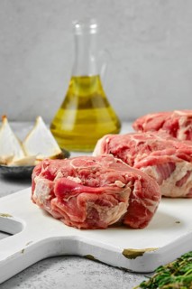 Uncooked raw lamb loin chops saddle steaks on wooden cutting board