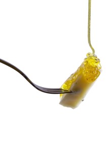 Piece of cheese on fork with floating honey