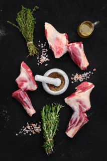 Fresh raw lamb ram shank with spice and herbs on dark background
