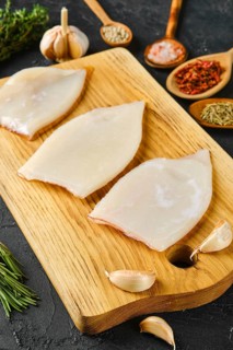 Raw frozen squid fillet on wooden cutting board