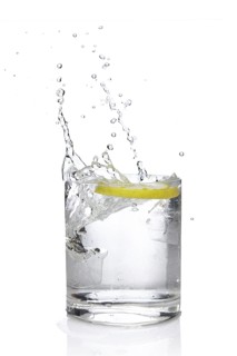 Ice cube and lemon splashing cocktail in oldfashioned glass. Drink with splashing citrus isolated on white