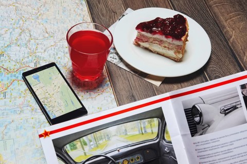 Cup of fruit-drink near map and smartphone with magazine on the table. Top point of view