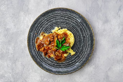 Top view of beef goulash with millet porridge and creamy sauce