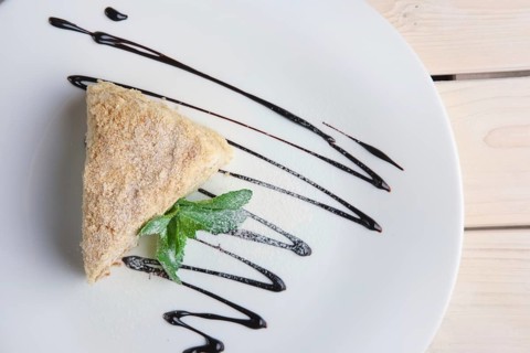 Top view of napoleon cake on plate with chocolate sauce. Puff pastry cake with custard