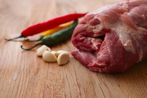 Fresh pork shoulder ready for baking with hot chilly and jalapeno pepper