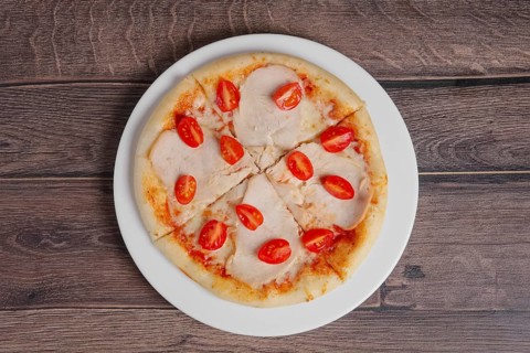 Pizza with ham and tomato on wooden table