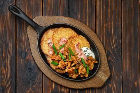 Top view of potato pancakes with chanterelles and pork in cast iron skillet