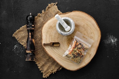 Wooden cross section with set for mulled wine spices in plastic package and stone mortar and mill