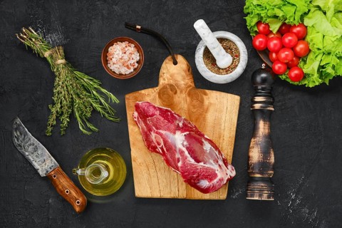 Overhead view of raw lamb rump on wooden cutting board