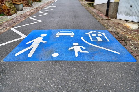 Blue play street symbol with playing children and car painted on road in Germany