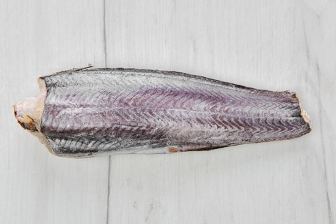 Frozen raw hake carcass on wooden table