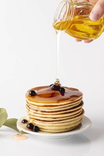 Front view honey poured pancake tower plate with blueberries