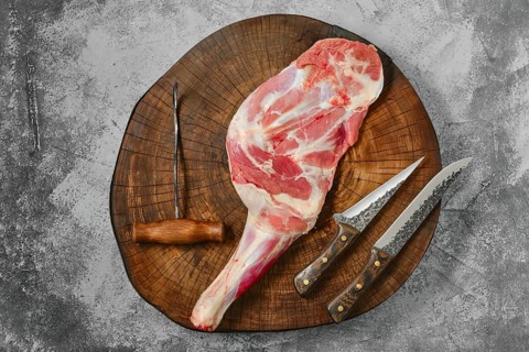 Raw fresh lamb shoulder chump on butcher's cutting log
