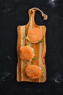 Overhead view of homemade burger with chicken cutlet on long wooden board