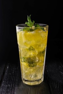 Faceted glass with cold citrus lemonade on dark wooden background