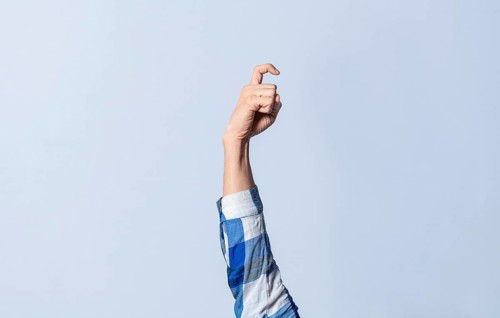 Hand gesturing the letter X in sign language on an isolated background. Man's hand gesturing the letter X of the alphabet isolated. Letter X of the alphabet in sign language